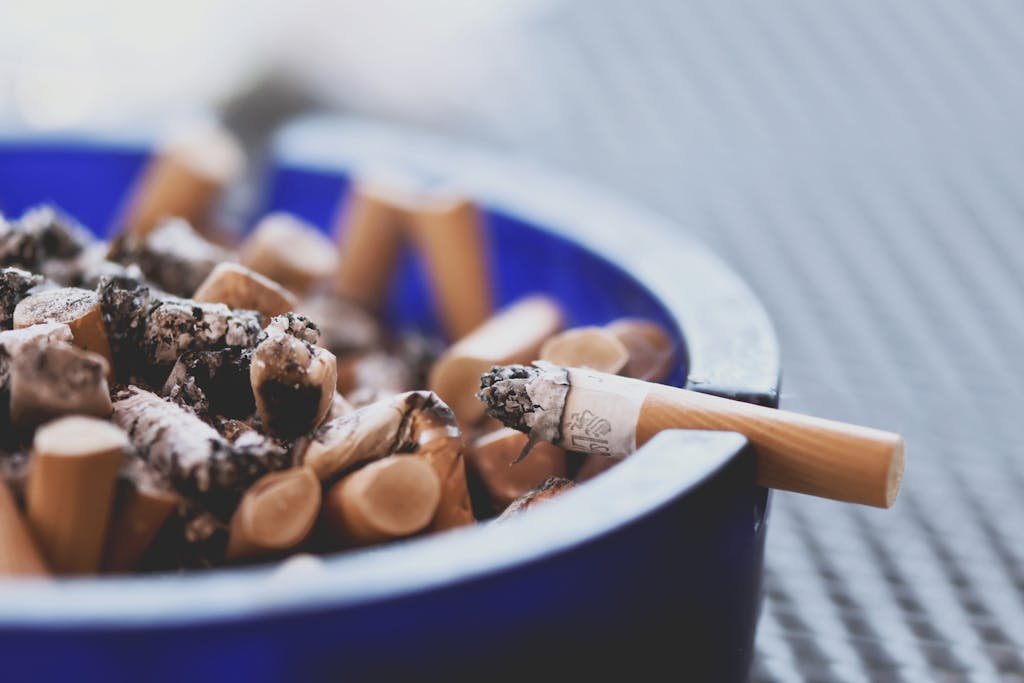 A close-up of cigarette butts in a blue ashtray, highlighting tobacco consumption.