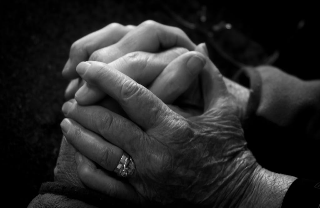 Close-up of intertwined elder and younger hands symbolizing care and connection.