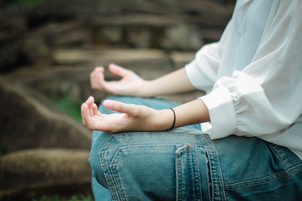 Person meditating outdoors, focusing on peace and relaxation.